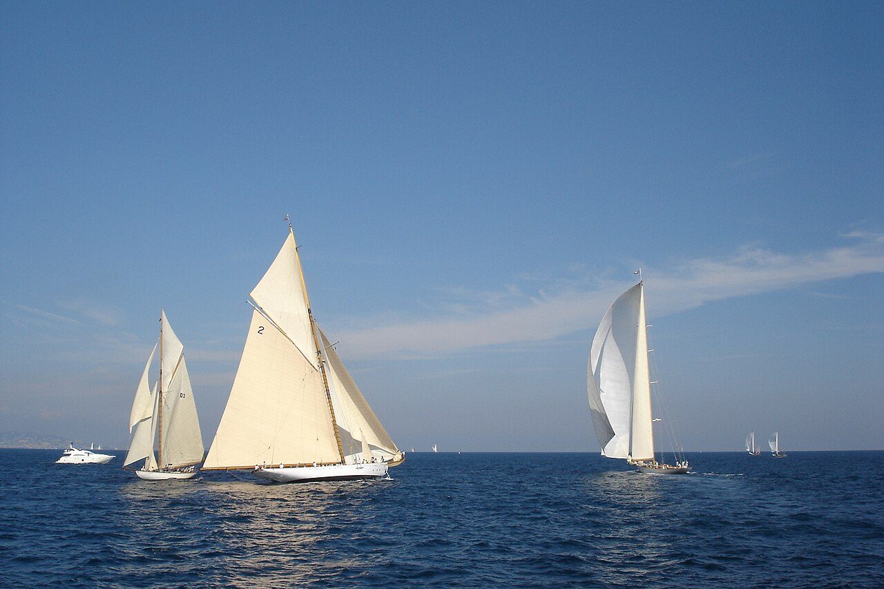 Klassiska segelyachter med gyllene segel på öppet hav