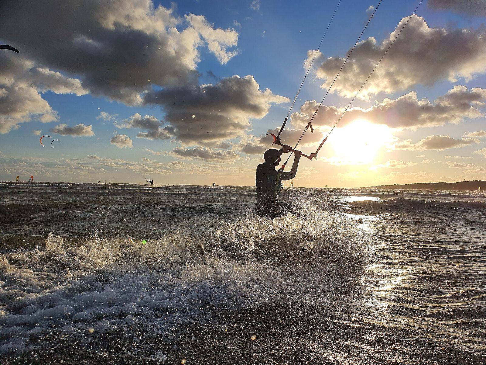 Kitesurfare i siluett mot solnedgången